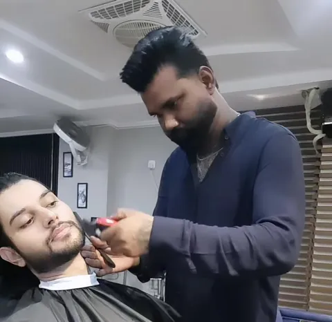 A barber shaping a client's beard